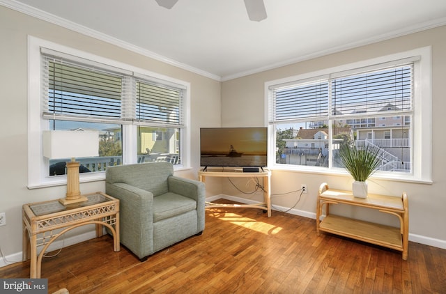 living area with plenty of natural light, wood-type flooring, baseboards, and ornamental molding