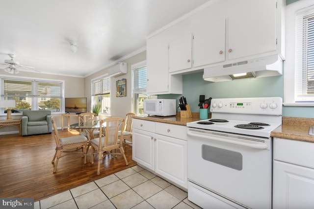 kitchen featuring white appliances, ornamental molding, an AC wall unit, white cabinets, and under cabinet range hood