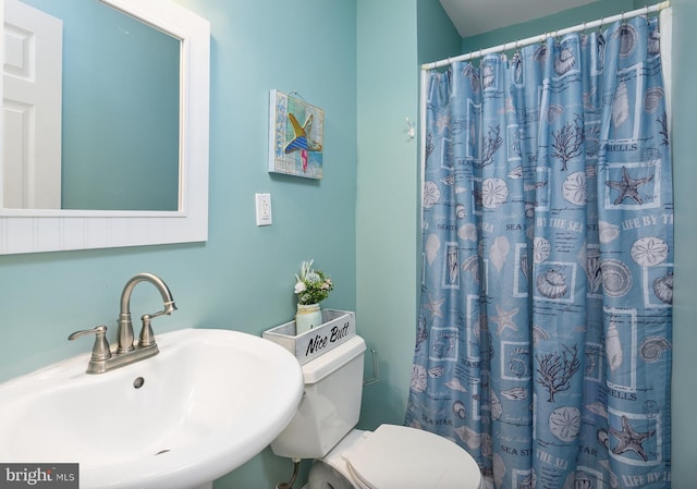 bathroom with curtained shower, toilet, and a sink