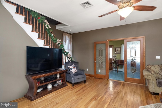 sitting room featuring visible vents, a ceiling fan, wood finished floors, stairway, and baseboards