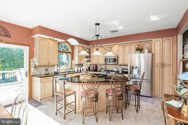 kitchen with a kitchen breakfast bar, dark countertops, appliances with stainless steel finishes, and light brown cabinets