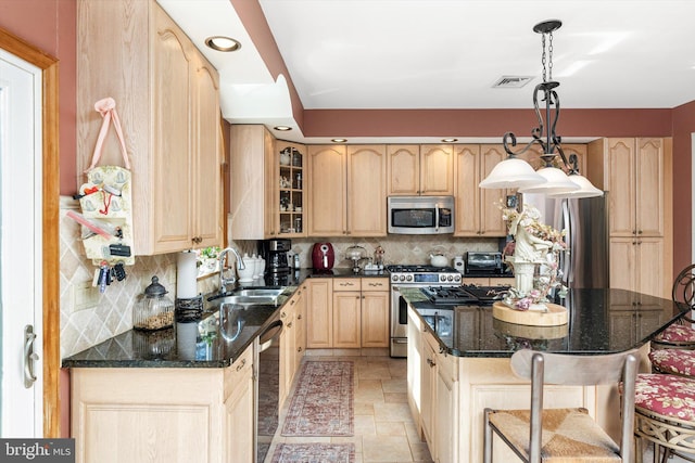 kitchen with light brown cabinets, appliances with stainless steel finishes, stone finish flooring, and a sink