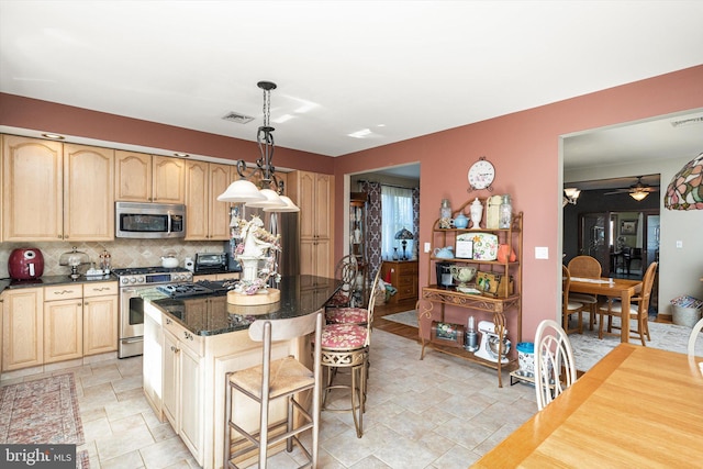 kitchen with tasteful backsplash, visible vents, a kitchen island, appliances with stainless steel finishes, and a kitchen breakfast bar