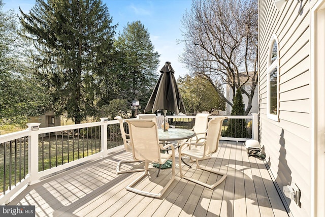 wooden deck with outdoor dining space and an outdoor structure