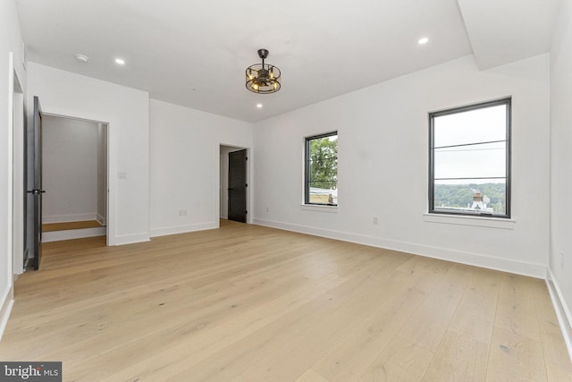 unfurnished bedroom with recessed lighting, light wood-type flooring, and a walk in closet