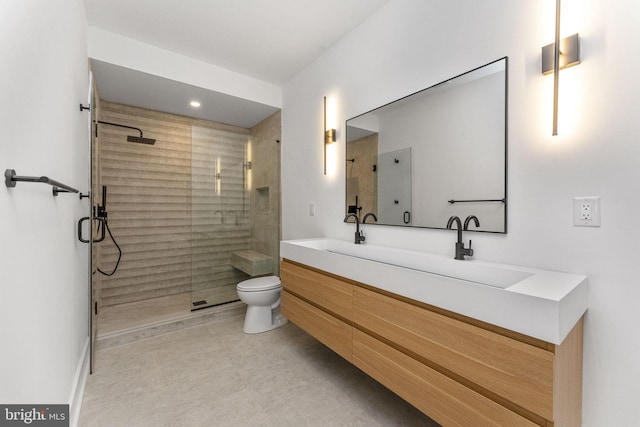 bathroom with double vanity, toilet, a stall shower, and a sink