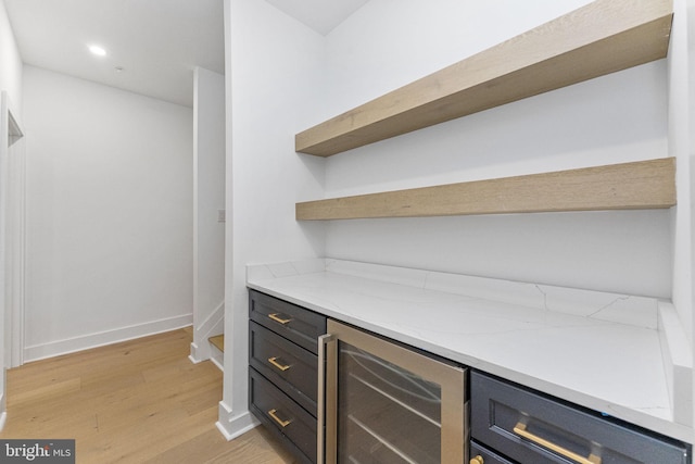 interior space featuring baseboards, light wood finished floors, recessed lighting, wine cooler, and a dry bar