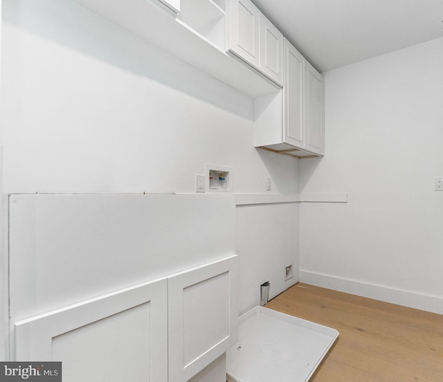 laundry area featuring washer hookup, cabinet space, light wood-type flooring, and baseboards