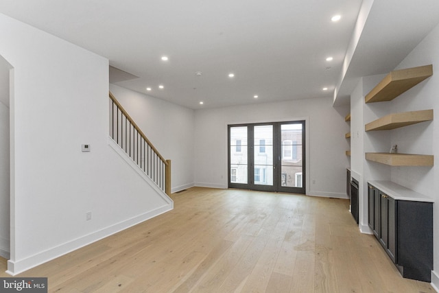 unfurnished living room featuring recessed lighting, stairway, baseboards, and light wood finished floors