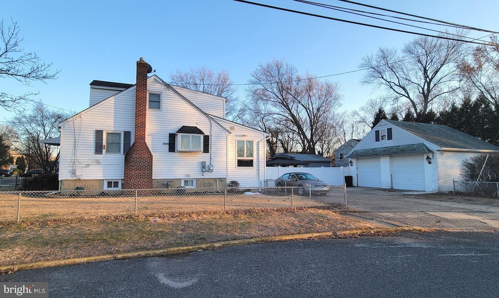 view of side of home with a fenced front yard, an outbuilding, and a chimney