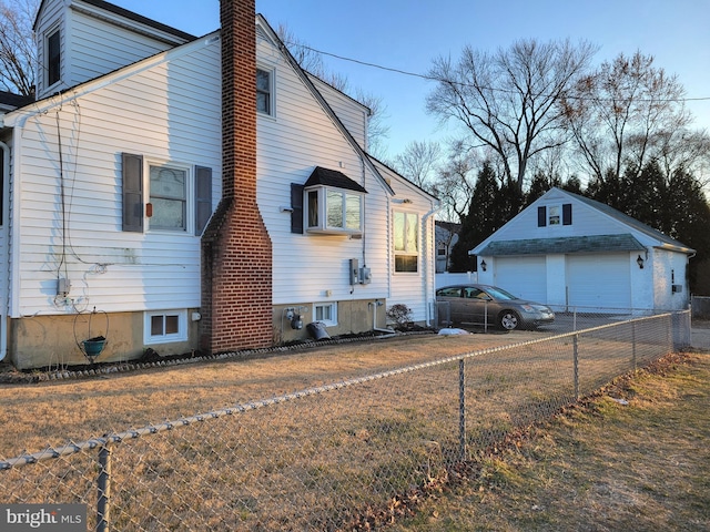 view of home's exterior with a detached garage, fence, and an outbuilding