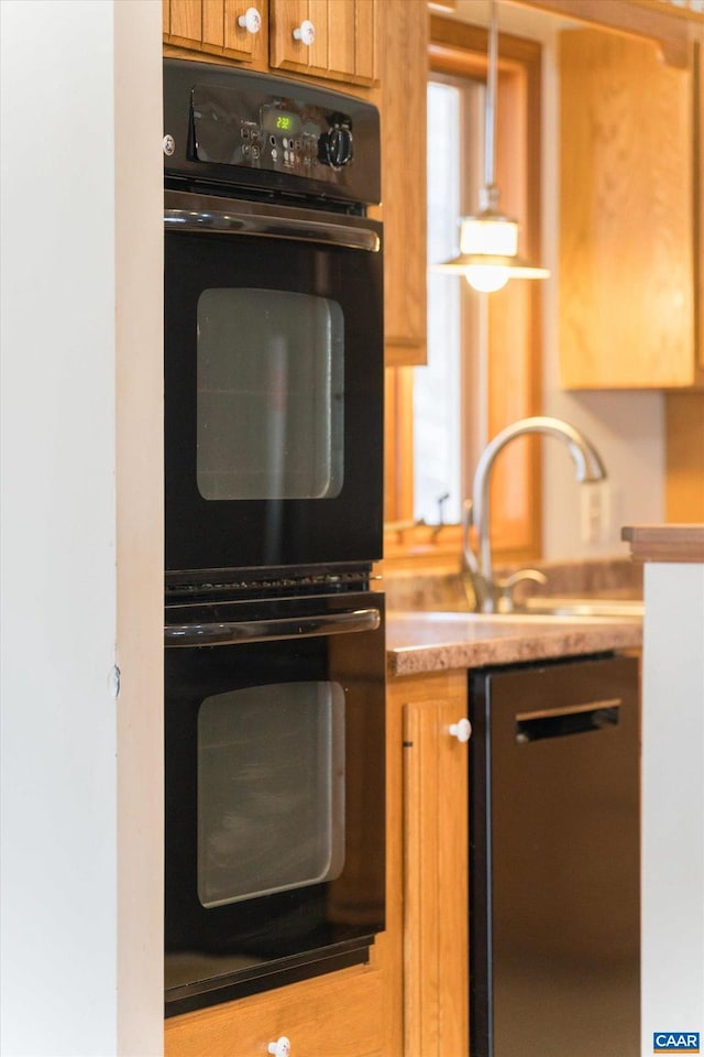 kitchen with black appliances, brown cabinetry, a sink, and light countertops