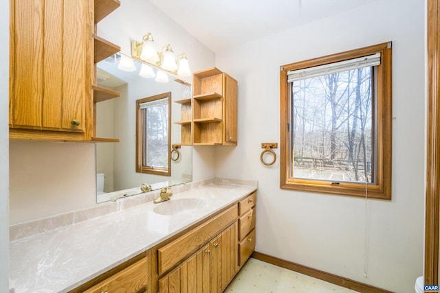 half bathroom featuring toilet, baseboards, and vanity