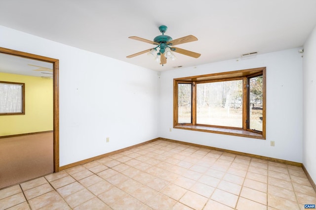 spare room with visible vents, ceiling fan, and baseboards