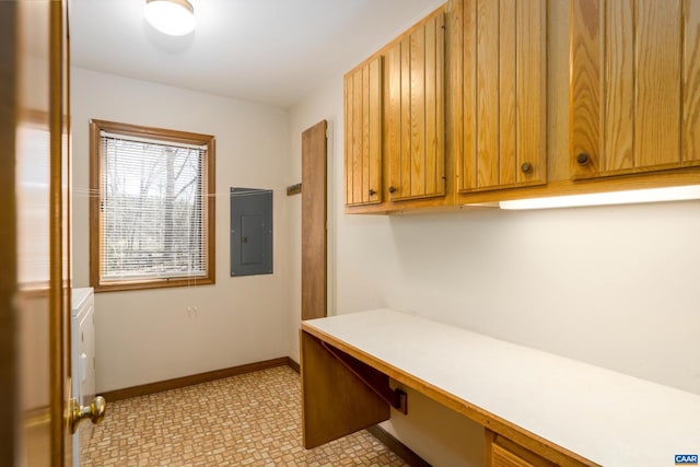 home office featuring built in desk, electric panel, and baseboards