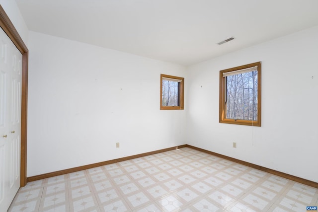 empty room with baseboards, visible vents, and light floors