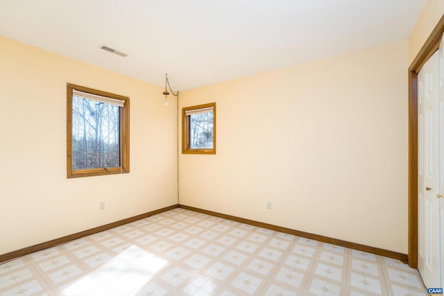 spare room with light floors, visible vents, and baseboards