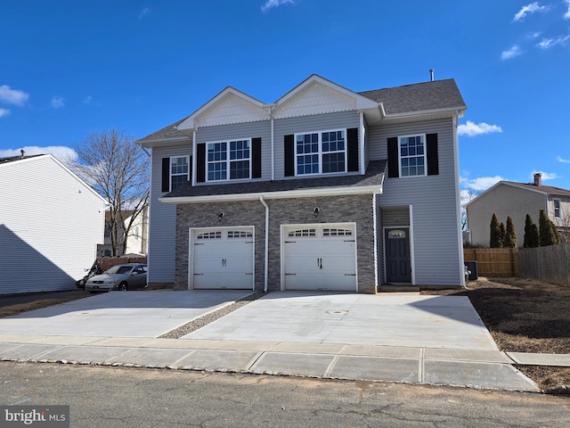 view of front of property with driveway, stone siding, an attached garage, and fence