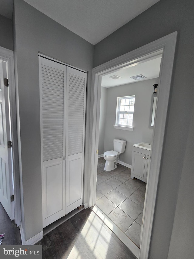 bathroom featuring visible vents, vanity, toilet, and baseboards