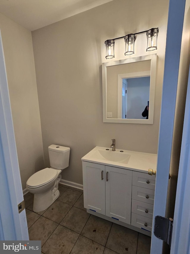 bathroom featuring toilet, tile patterned flooring, baseboards, and vanity