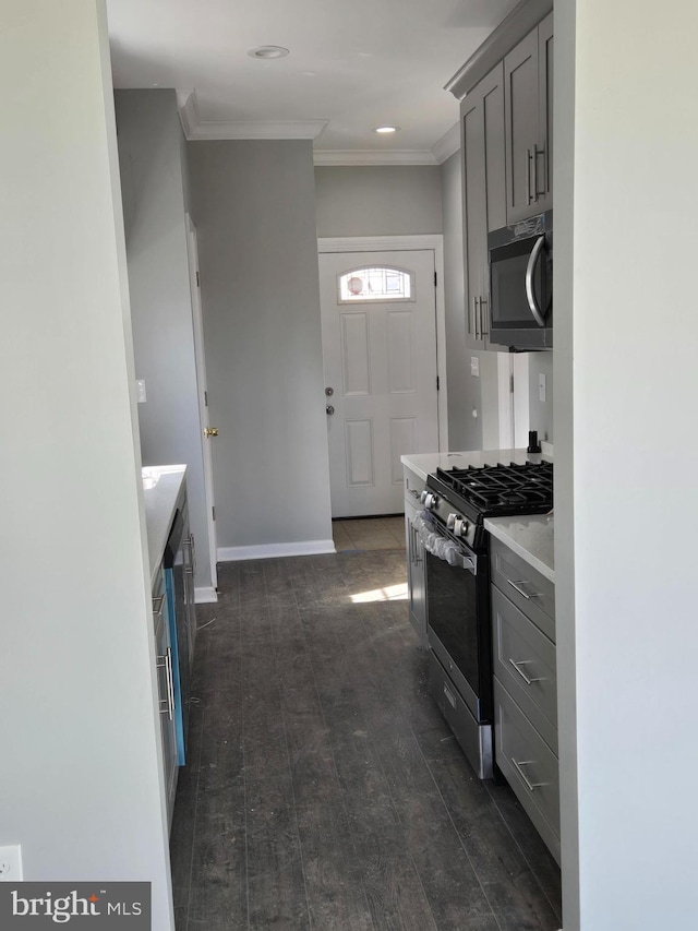 kitchen with stainless steel gas stove, dark wood-type flooring, gray cabinets, crown molding, and light countertops