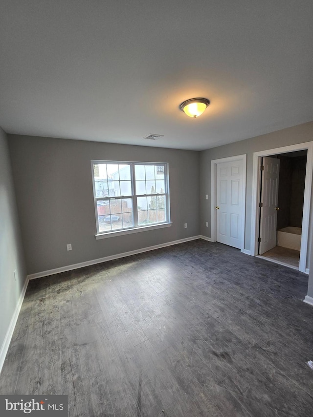 unfurnished bedroom featuring baseboards, visible vents, and dark wood-type flooring