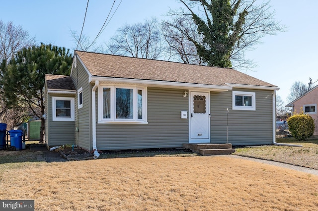 view of front of property with roof with shingles and a front lawn