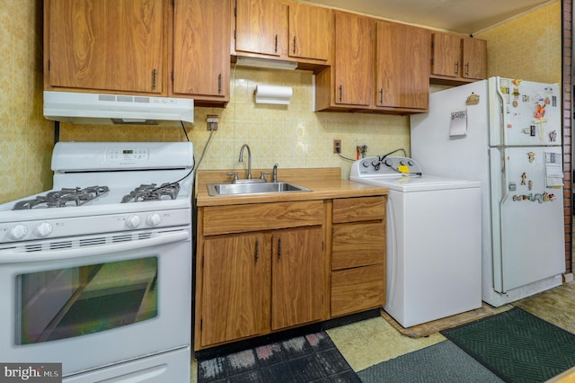 kitchen with under cabinet range hood, white appliances, a sink, light countertops, and washer / clothes dryer