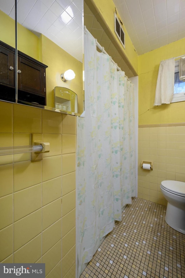 full bathroom featuring tile patterned flooring, visible vents, tile walls, and toilet