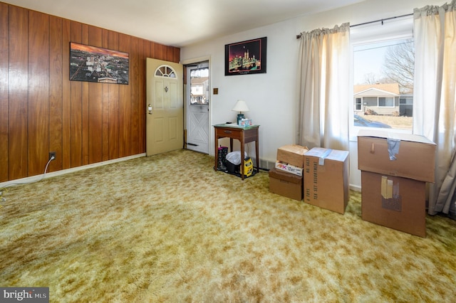 entrance foyer with carpet floors, wooden walls, and baseboards