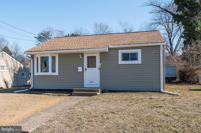 bungalow-style home featuring a shingled roof and a front lawn