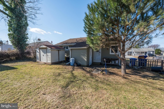 rear view of property with fence, a storage unit, an outdoor structure, and a yard