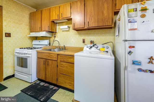 kitchen featuring a sink, washer / dryer, white appliances, under cabinet range hood, and wallpapered walls