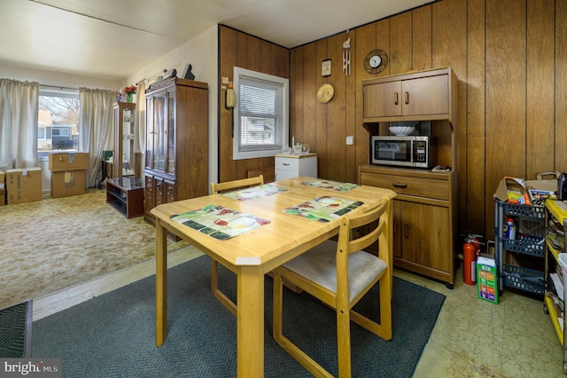 dining space featuring wooden walls and light colored carpet