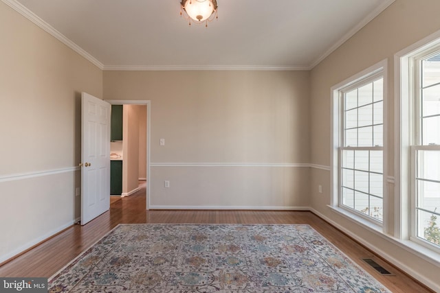 unfurnished room featuring visible vents, baseboards, wood finished floors, and crown molding