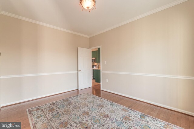 unfurnished room featuring ornamental molding, baseboards, and wood finished floors