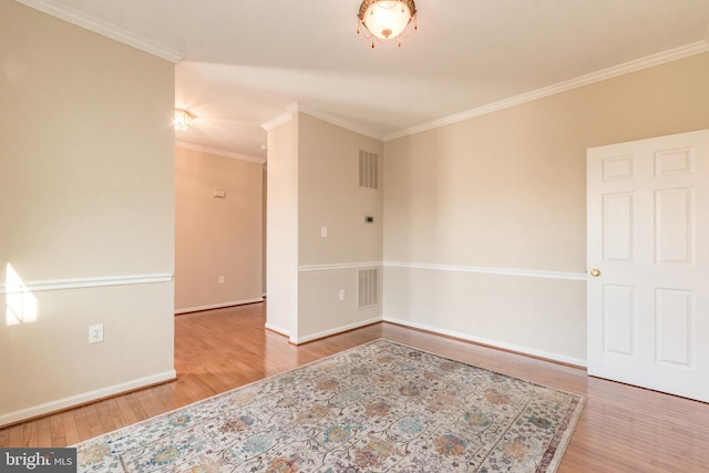 unfurnished room featuring wood finished floors, visible vents, and ornamental molding