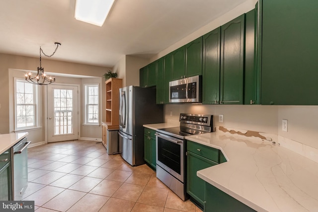 kitchen with green cabinetry, stainless steel appliances, an inviting chandelier, and light tile patterned flooring