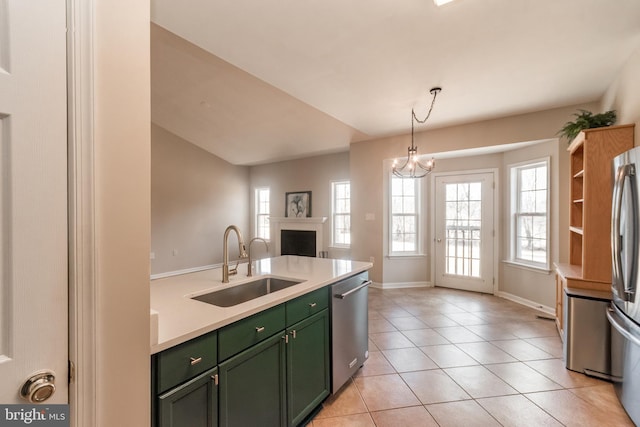 kitchen featuring a sink, appliances with stainless steel finishes, a fireplace, green cabinetry, and light tile patterned floors