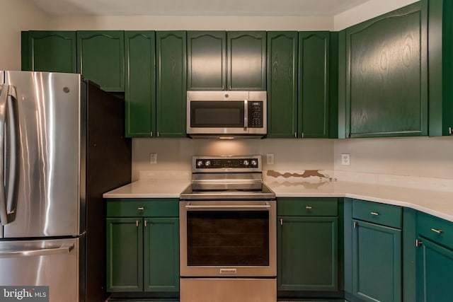 kitchen featuring stainless steel appliances, green cabinets, and light countertops