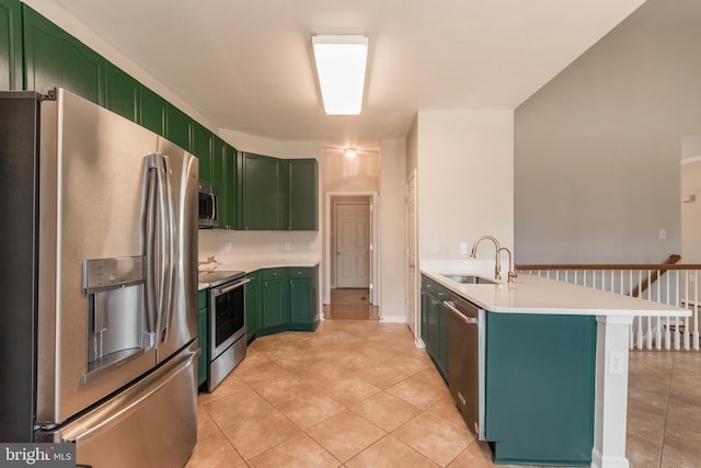 kitchen featuring a sink, appliances with stainless steel finishes, a peninsula, light countertops, and green cabinetry