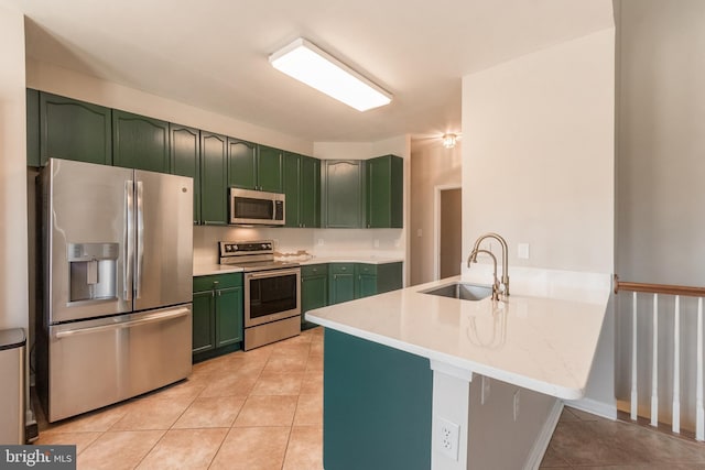 kitchen featuring green cabinetry, light tile patterned floors, a peninsula, stainless steel appliances, and a sink