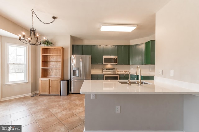 kitchen featuring light tile patterned floors, green cabinetry, a peninsula, a sink, and stainless steel appliances