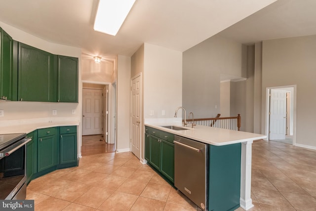 kitchen featuring a sink, a peninsula, appliances with stainless steel finishes, green cabinets, and light countertops