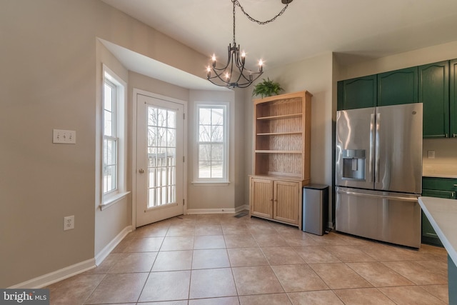 kitchen featuring green cabinets, stainless steel fridge with ice dispenser, light countertops, an inviting chandelier, and light tile patterned flooring