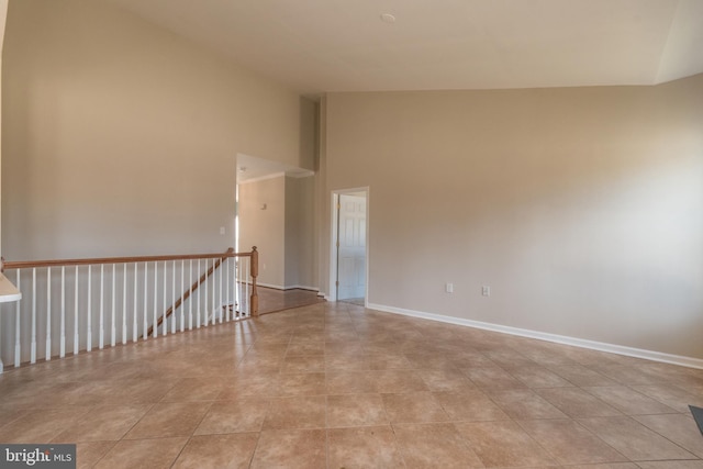 spare room featuring light tile patterned floors, high vaulted ceiling, and baseboards