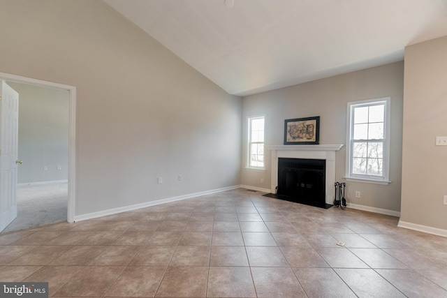 unfurnished living room with a fireplace with flush hearth, light tile patterned flooring, baseboards, and high vaulted ceiling