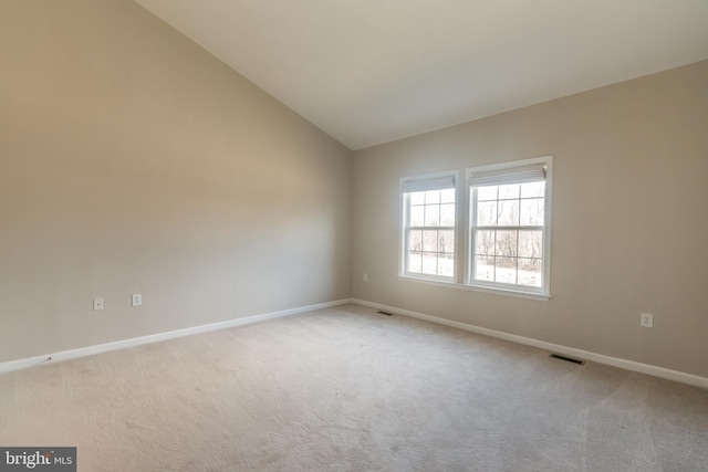 spare room with vaulted ceiling, baseboards, visible vents, and light carpet