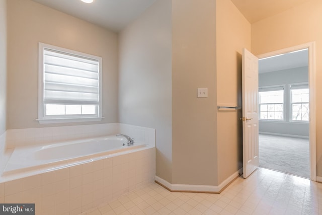 bathroom featuring tile patterned flooring, a bath, and baseboards