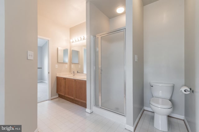 bathroom featuring vanity, toilet, baseboards, and a stall shower